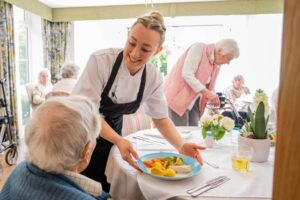Dementia care home residents enjoying a supported mealtime in a UK care setting